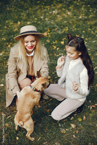 Mother and her daughter with a little puppy french bulldog in a park