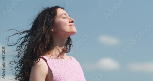 Happy relaxed woman breathing fresh air raising arms over blue sky at summer, Dreaming, freedom and traveling concept. photo