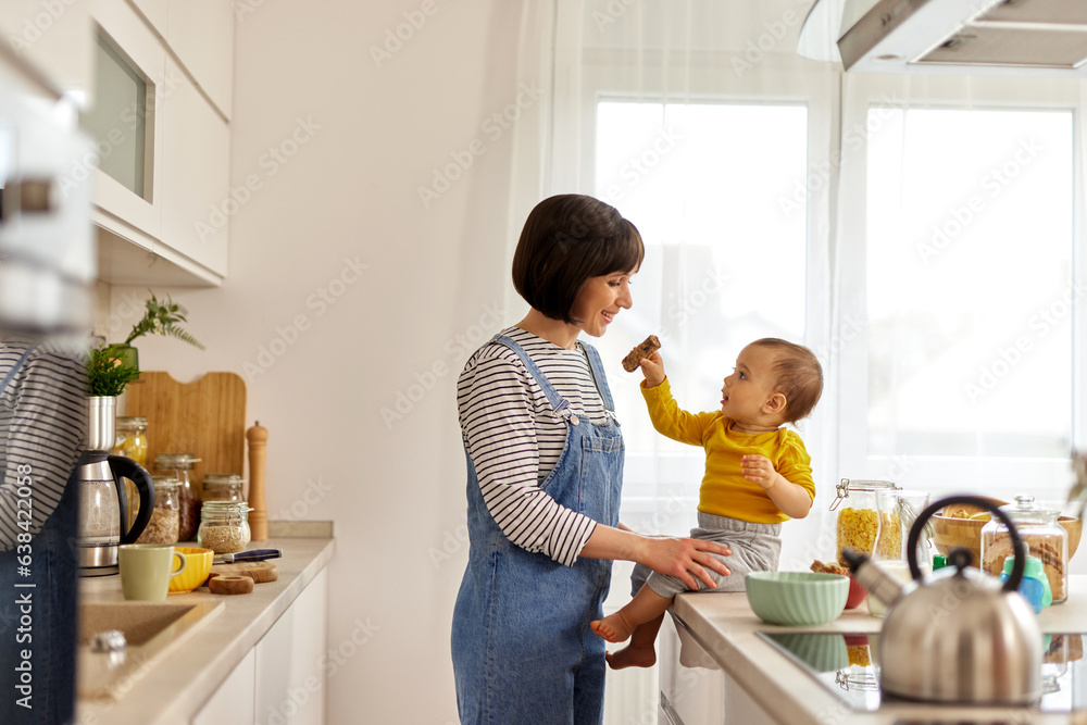 Baby boy feeding his mother in the kitchen Baby boy feeding his mother in the kitchen