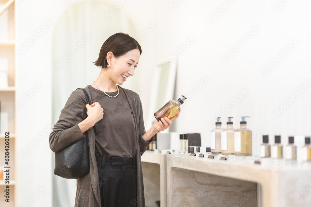 Fototapeta premium 店舗で商品を手に取り選んでいる日本人女性/ショッピング