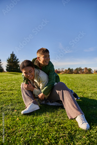 happy mother and son in park, sunny day, autumn, playful african american boy hugging mom, diversity © LIGHTFIELD STUDIOS