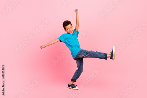 Full length photo of pretty excited little boy dressed blue t-shirt walking dancing isolated pink color background