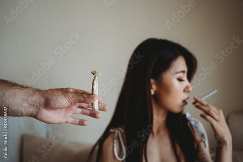 Man passing woman psychedelic mushroom while she is smoking a cigarette
