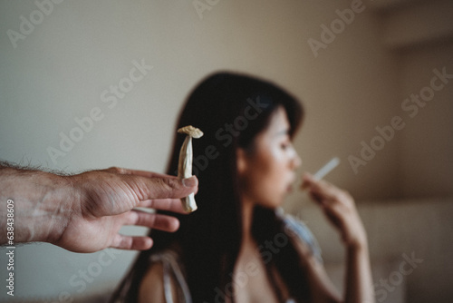 Woman smoking someone passing her a psychedelic mushroom