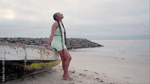 Woman sitting on fishing boat in the beach cloudy morning on winter