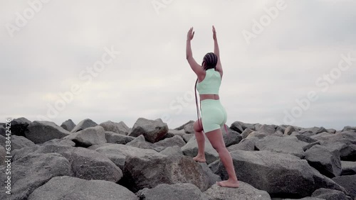 Woman doing yoga in the rock stretching in cloudy morning on winter