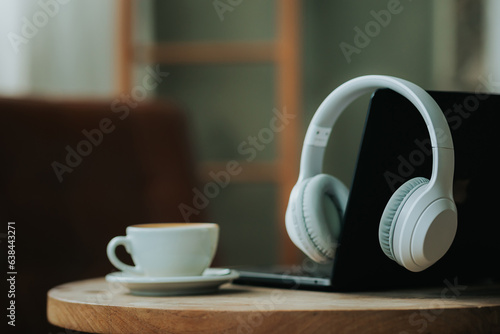 Workplace concept, laptop, headphones and coffee cup on wooden table in house independent home office
