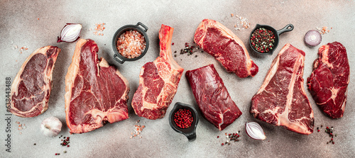 Variety of Raw Black Angus Prime meat steaks T-bone, tomahawk, New York steak. Set raw marbled beef strip loin steaks. place for text, top view