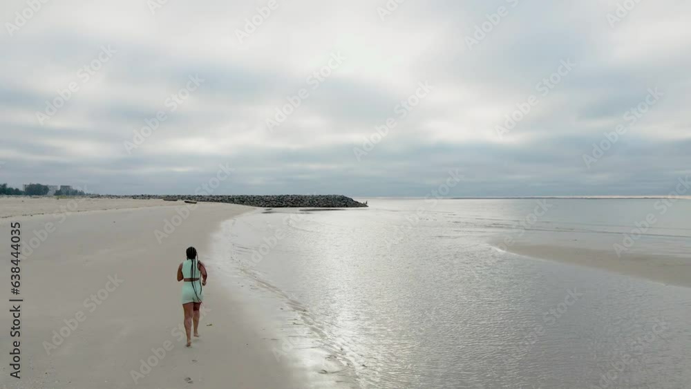 Woman running on the beach in cloudy morning on winter Woman running on the beach in cloudy morning on winter