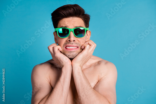 Photo portrait of handsome young guy frightened shock bite fingers shirtless isolated on blue color background summer vacation