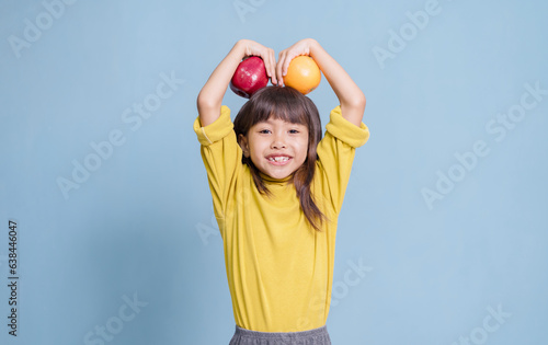 A little girl is fond of eating fruit and holding fruit.
