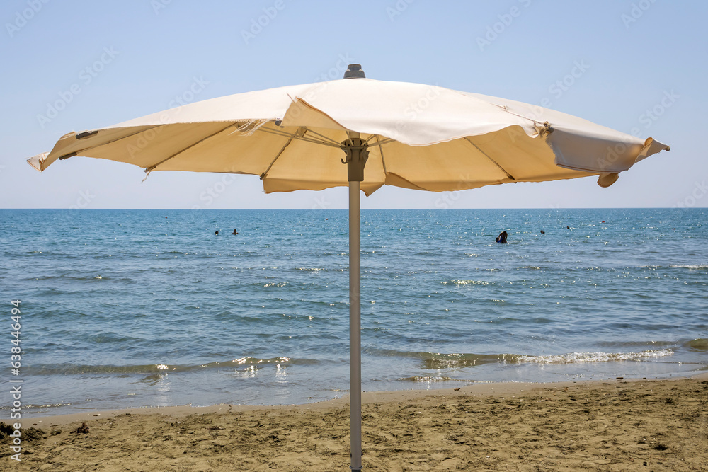 Parasol on sandy beach in front of blue sea and sky, Cyprus
