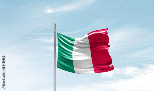 Italy national flag waving in beautiful sky. The symbol of the state on wavy silk fabric.
