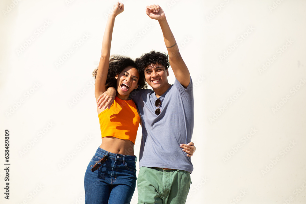 cheerful young couple with arms raised by white background cheerful young couple with arms raised by white background