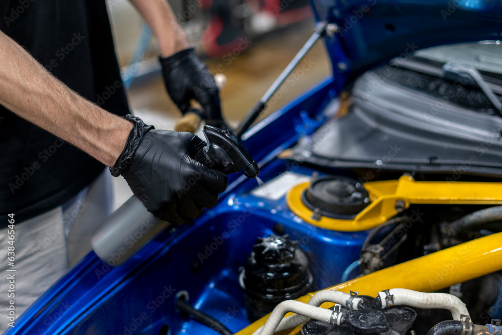 detailing master cleans the engine compartment of a car at a car wash detailing master cleans the engine compartment of a car at a car wash