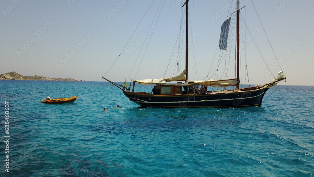Yacht, sailing in Greece and summer on ocean holiday, relax in freedom and people swimming in blue water. Boat vacation, travel in sun and tropical cruise on sea adventure with island beach fun.