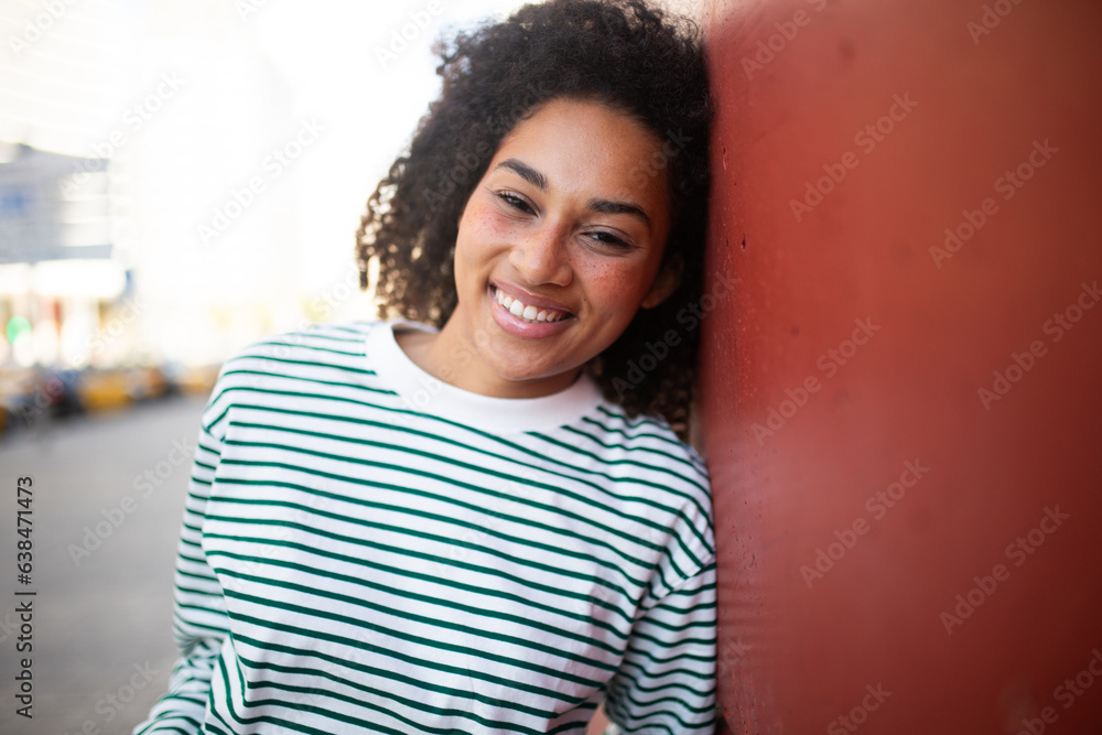 Fototapeta premium happy young african american woman leaning against wall