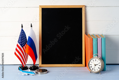 Blank blackboard with USA and Russia flags on wooden background photo