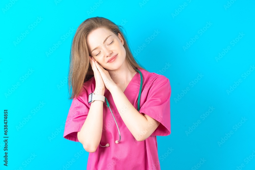young beautiful red haired doctor woman sleeping tired dreaming and posing with hands together while smiling with closed eyes. young beautiful red haired doctor woman sleeping tired dreaming and posing with hands together while smiling with closed eyes.