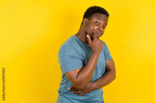 Young handsome man standing over yellow studio background Pointing to the eye watching you gesture, suspicious expression.