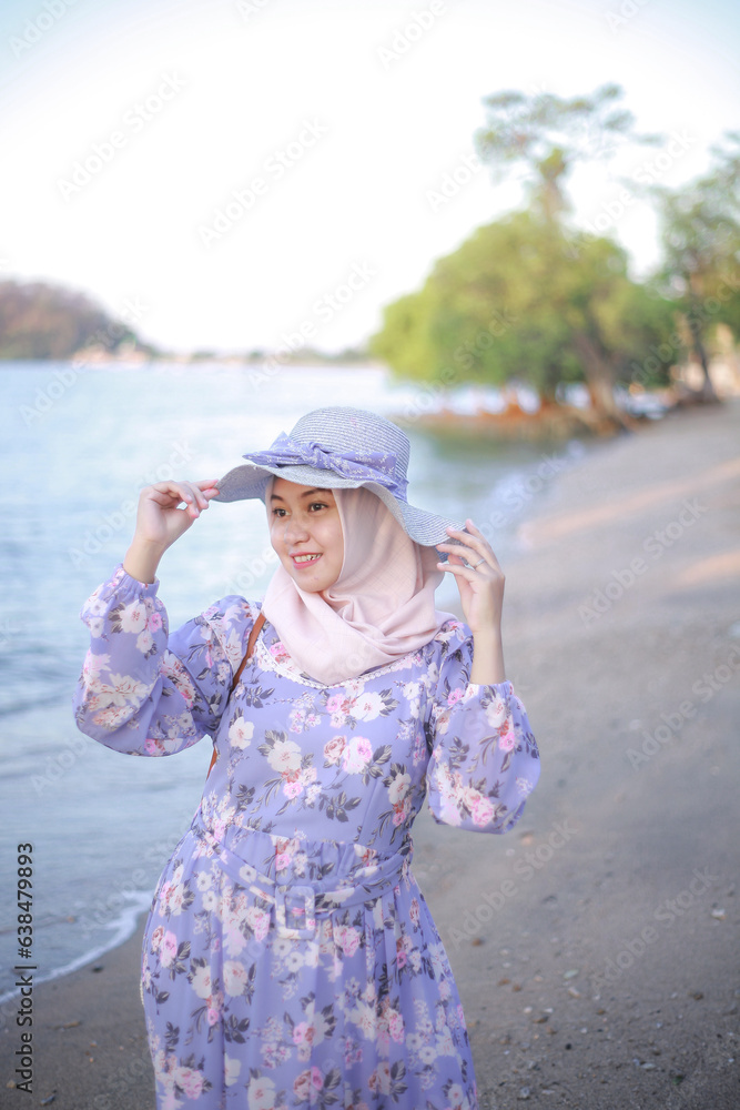 A young Hijab girl wearing beach hat is relaxing on the beach, Indonesia