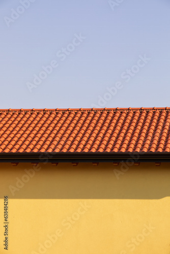 Tetto di tegole rosse sulla parete gialla di una casa nel villaggio. Fotografia verticale.