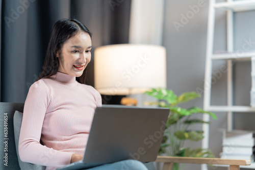  beautiful lady using laptop on the couch of her house.