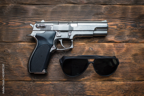 Toy gun and sunglasses on the detective wooden table flatlay background concept. Secret service. Spy desk background.