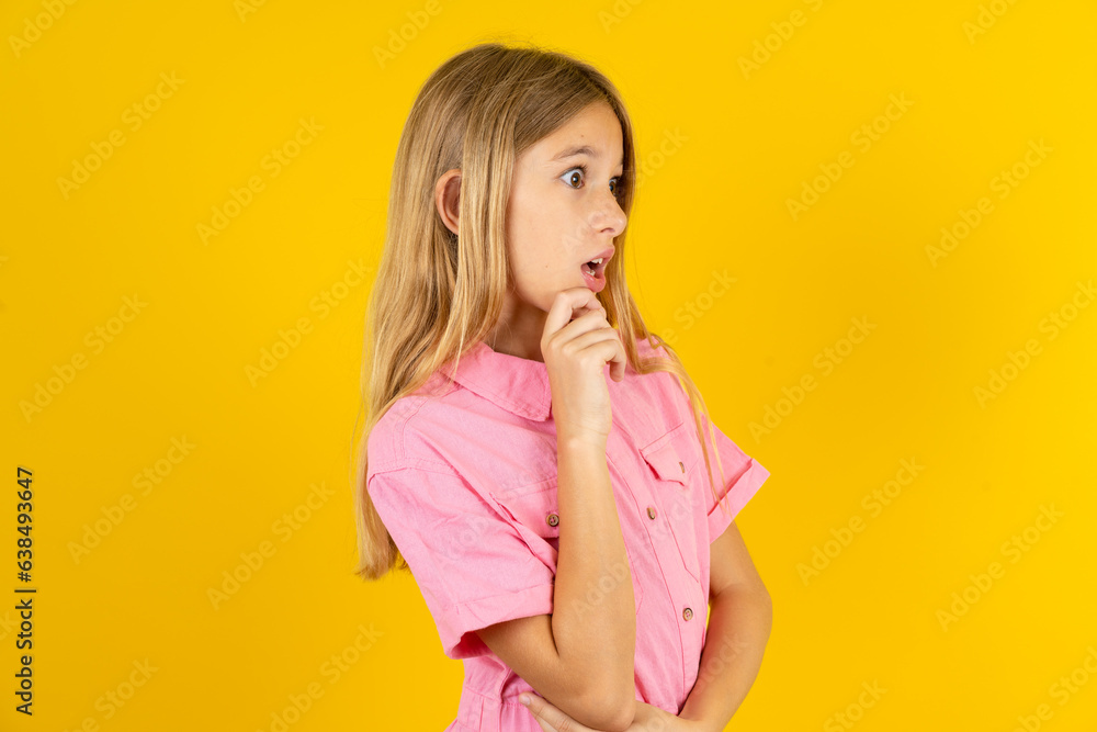 Astonished Beautiful caucasian kid girl wearing pink shirt looks aside surprisingly with opened mouth. Astonished Beautiful caucasian kid girl wearing pink shirt looks aside surprisingly with opened mouth.