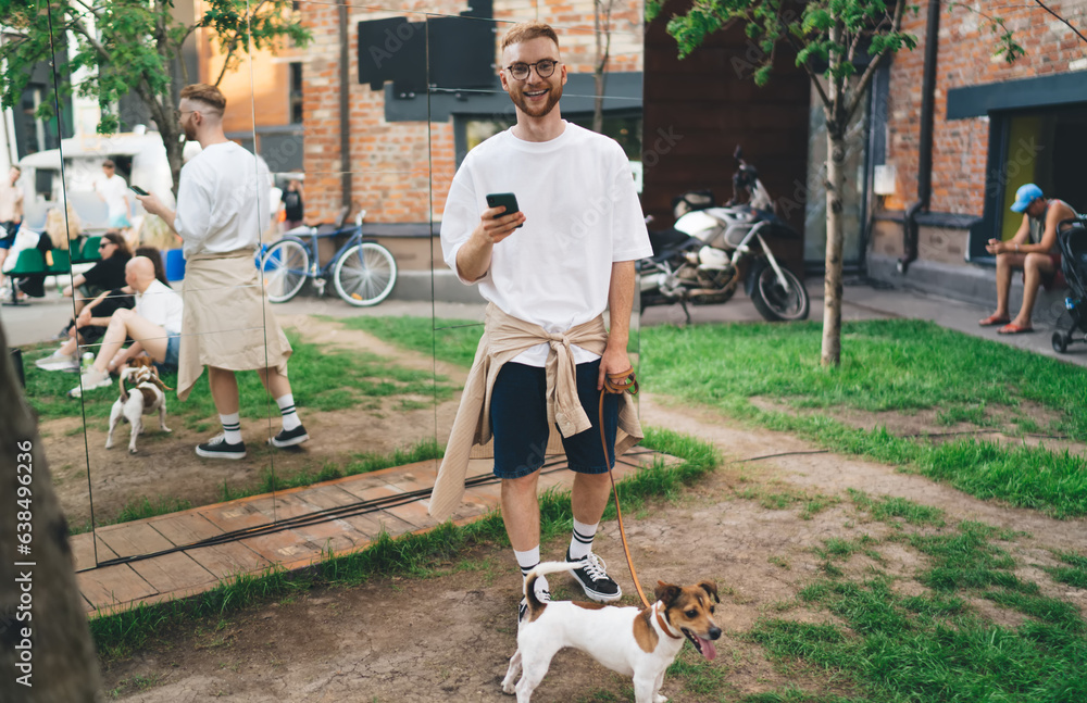 Obraz premium Happy man using cellphone with dog in park