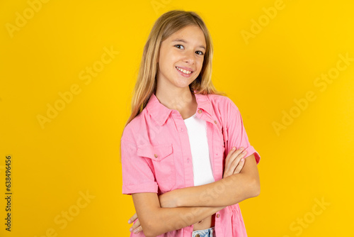 Portrait of charming Beautiful caucasian kid girl wearing pink shirt standing confidently smiling toothily with hands folded