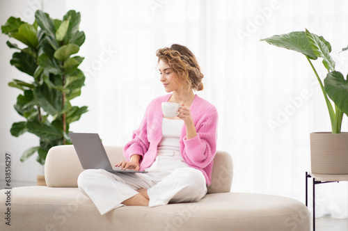 Portrait Of Beautiful Young Lady Using Laptop And Drinking Tea At Home