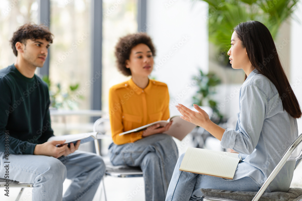 Diverse university students having a group discussion sitting together in classroom in circle of chairs Diverse university students having a group discussion sitting together in classroom in circle of chairs