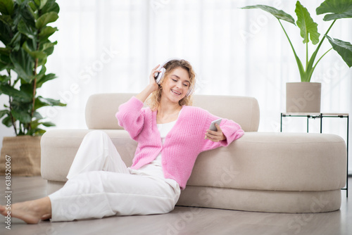Relaxed young woman listening music on smartphone with wireless headphones
