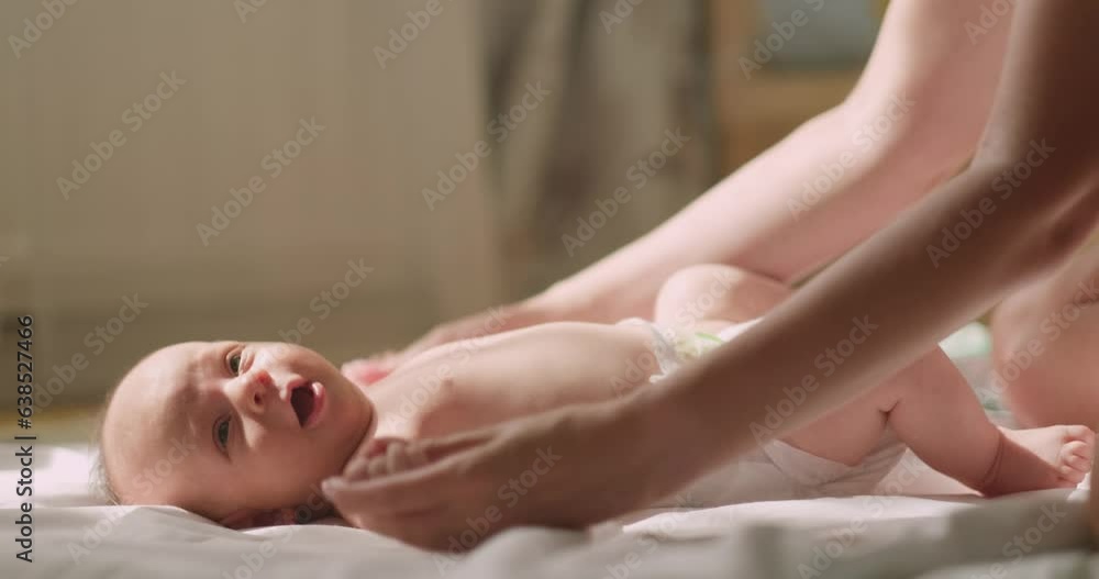 Baby massage, Mother massaging her baby at home, making exercises, atmospheric sun light