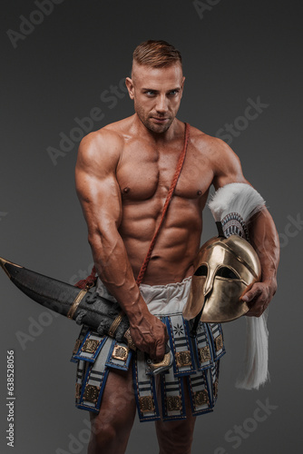 Ancient Greek hoplite warrior, displaying his muscular physique and strength as he stands poised with a helmet and spear, surrounded by a minimalist grey setting