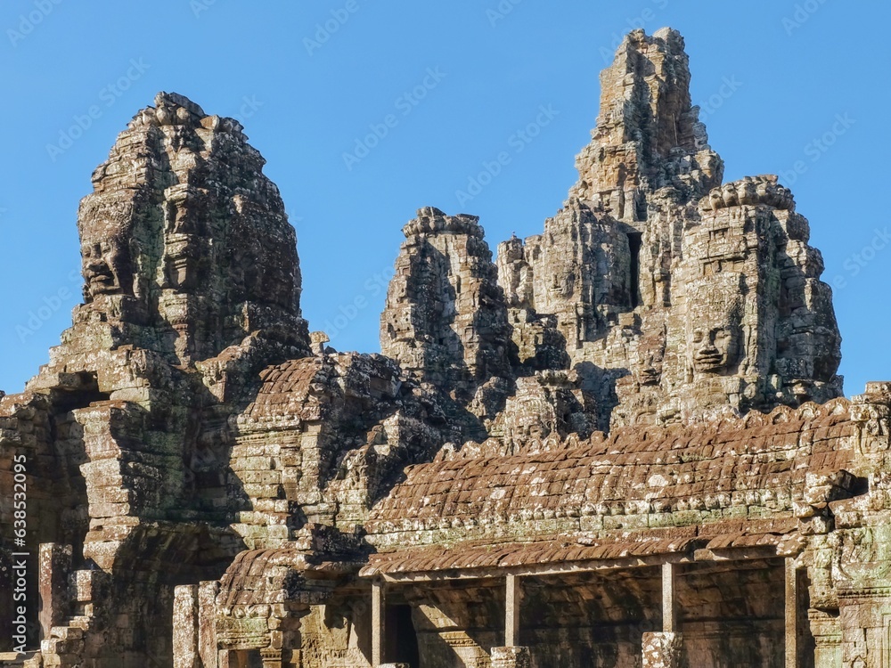 Scenic view of the stone towers of the medieval Khmer Bayon Temple under a blue sky in Cambodia.