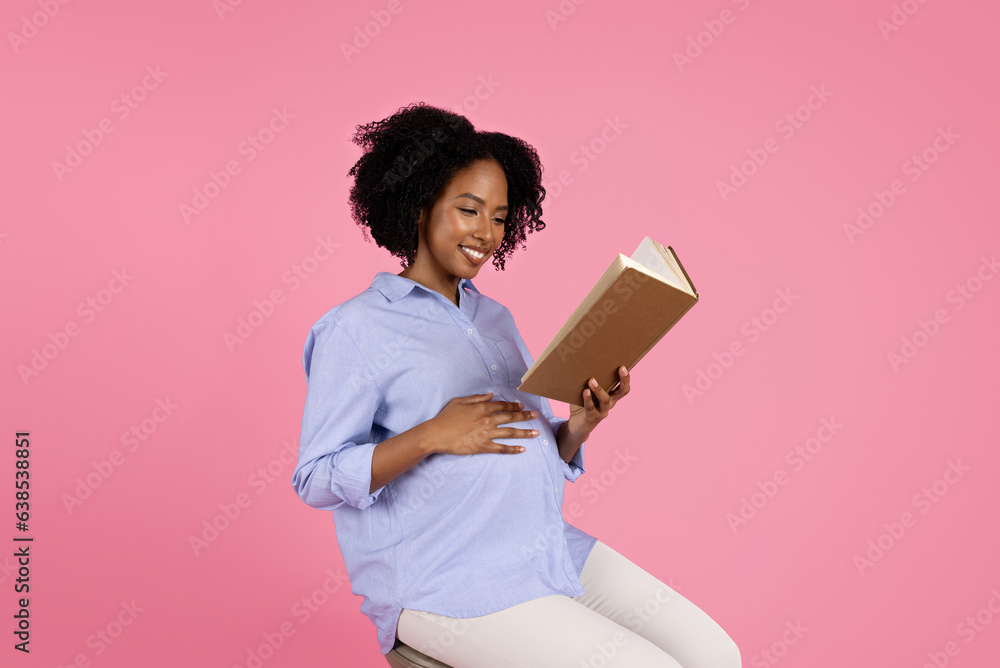Smiling young black pregnant woman in casual with big belly reading book Smiling young black pregnant woman in casual with big belly reading book