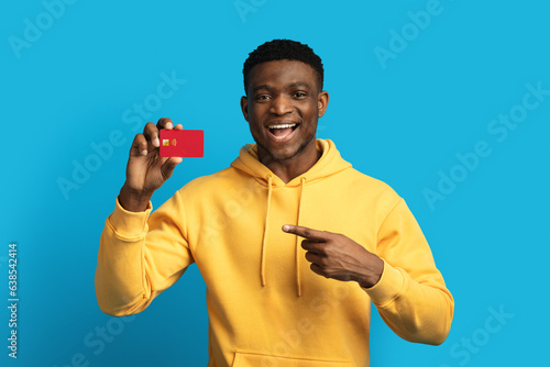 Cheerful handsome young blank man holding red bank credit card photo