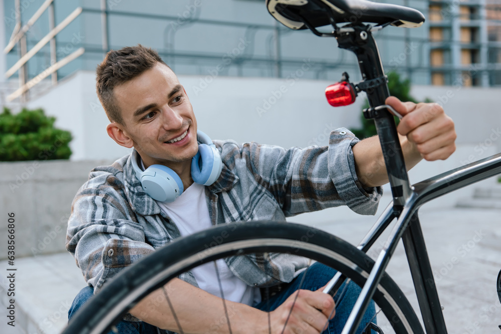 Obraz premium Good-looking young man fixing a problem with a bike tire
