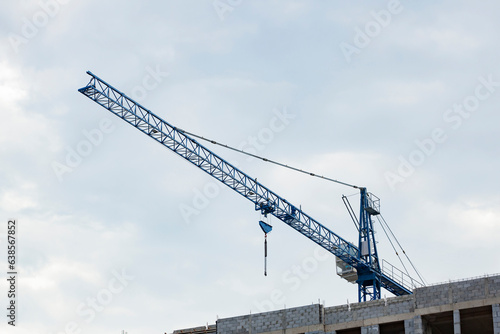 Crane on the background of a cloudy sky. Construction of storey buildings.