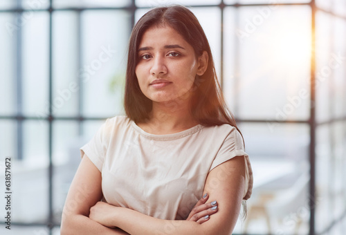 Free Download Portrait of a confident young businesswoman standing with her arms crossed in an office - GFXLoad