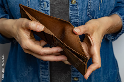 A woman holds an empty wallet in her hands. The concept of poverty.