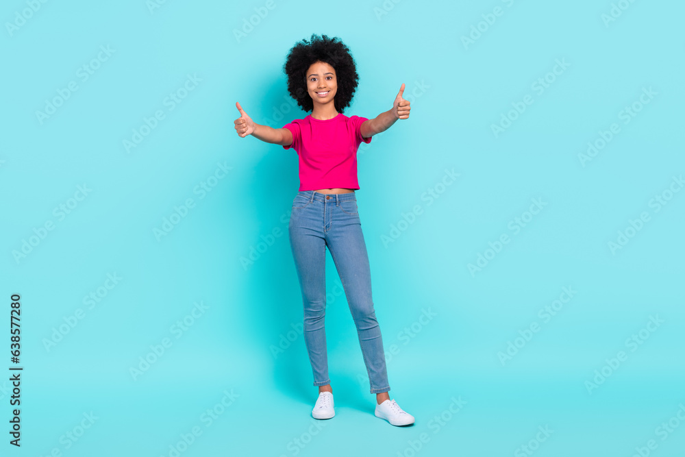 Full length portrait of satisfied charming small girl hands fingers demonstrate thumb up approval isolated on turquoise color background Full length portrait of satisfied charming small girl hands fingers demonstrate thumb up approval isolated on turquoise color background