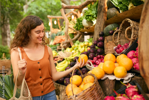 Female Customer At Market Stall Choosing Fresh Fruit And Vegetables