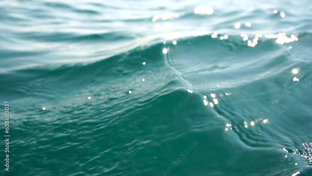 Sea water surface. Camera flies over the calm azure sea with volcanic rocky shores on background. Nobody. Holiday recreation concept. Abstract nautical summer ocean nature. Slow motion. Close up Sea water surface. Camera flies over the calm azure sea with volcanic rocky shores on background. Nobody. Holiday recreation concept. Abstract nautical summer ocean nature. Slow motion. Close up