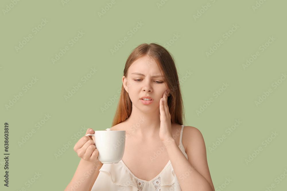 Young woman with sensitive teeth and cup of hot coffee on green background Young woman with sensitive teeth and cup of hot coffee on green background