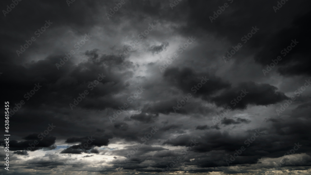 Fototapeta premium dark dramatic sky with black stormy clouds before rain or snow as abstract background, extreme weather, the sun shines through the clouds, high contrast photo