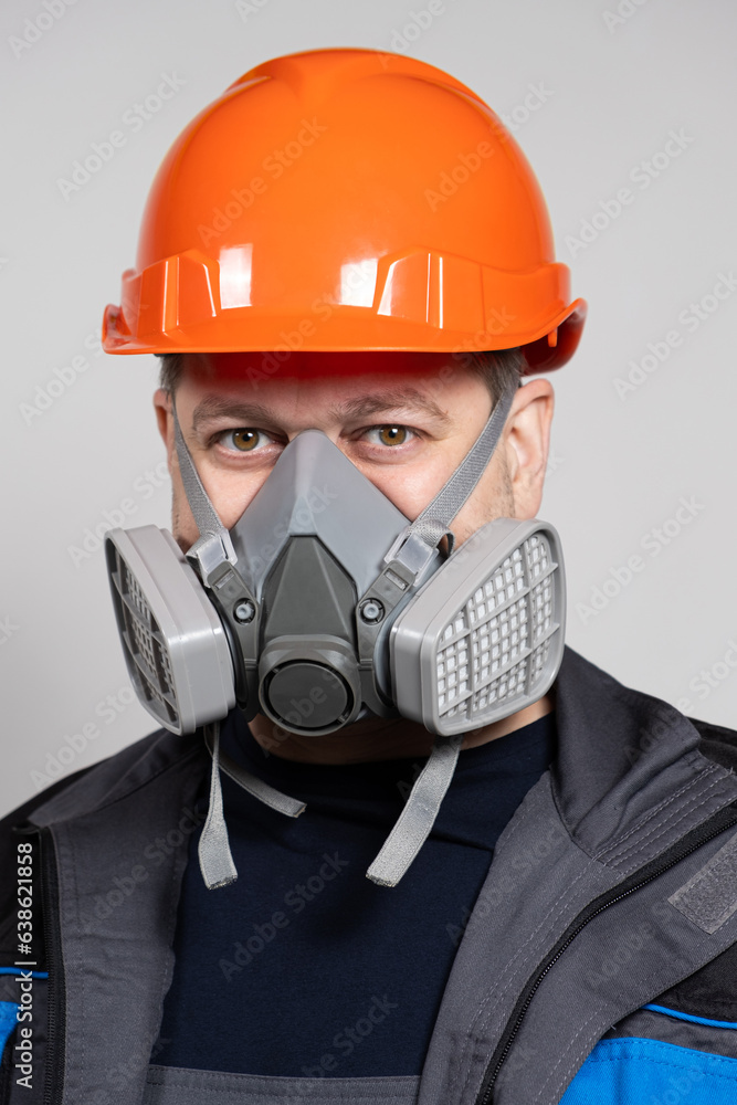 A man wearing a safety helmet and a respirator to protect against dust and gases on a white background. A man wearing a safety helmet and a respirator to protect against dust and gases on a white background.