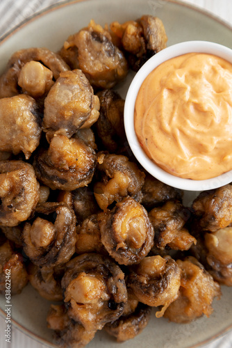 Homemade Crispy Deep Fried Mushrooms with Spicy Mayo on a Plate on a white wooden background, top view.